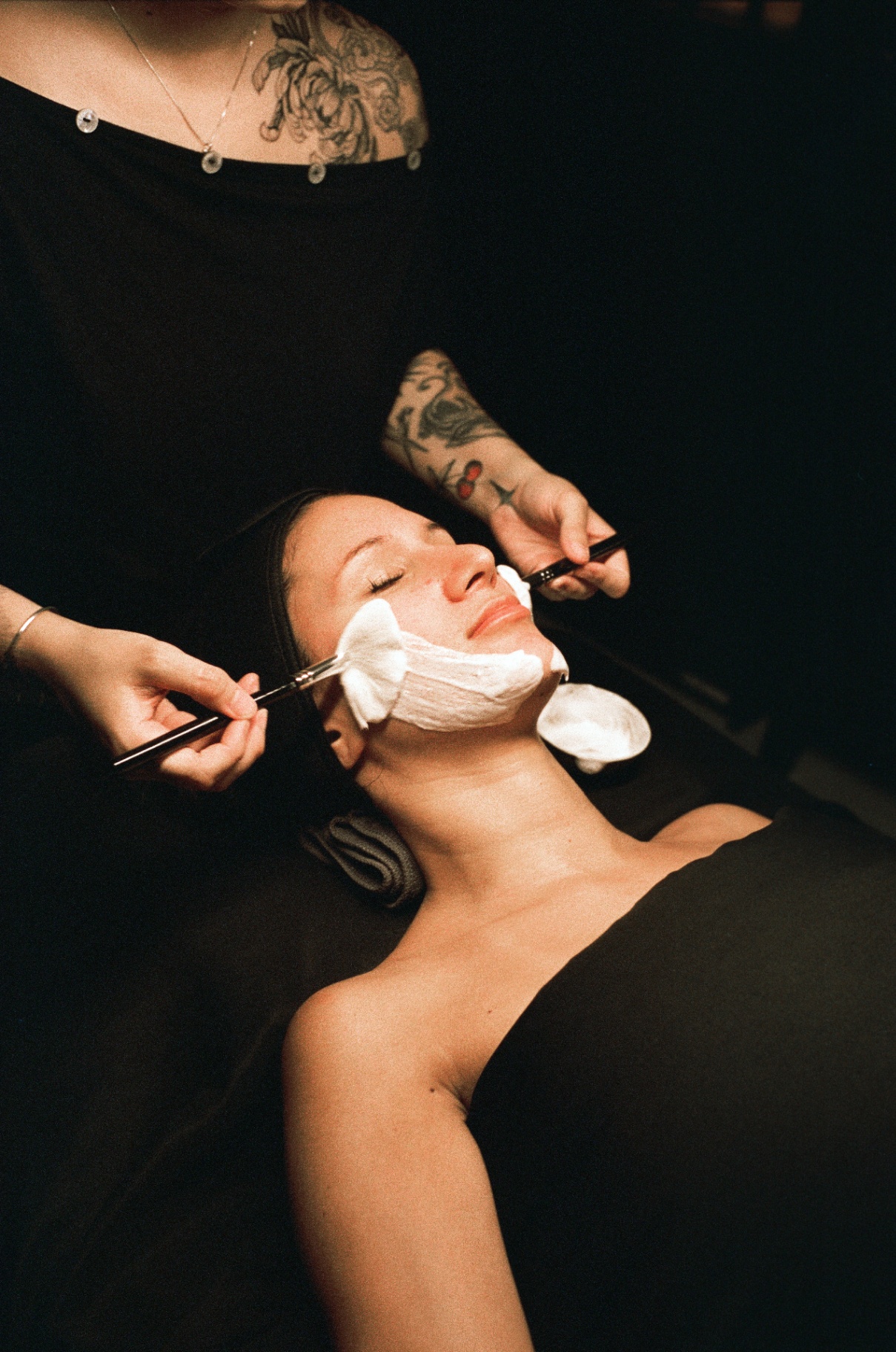 Esthetician applying mask with brushes to a client's face