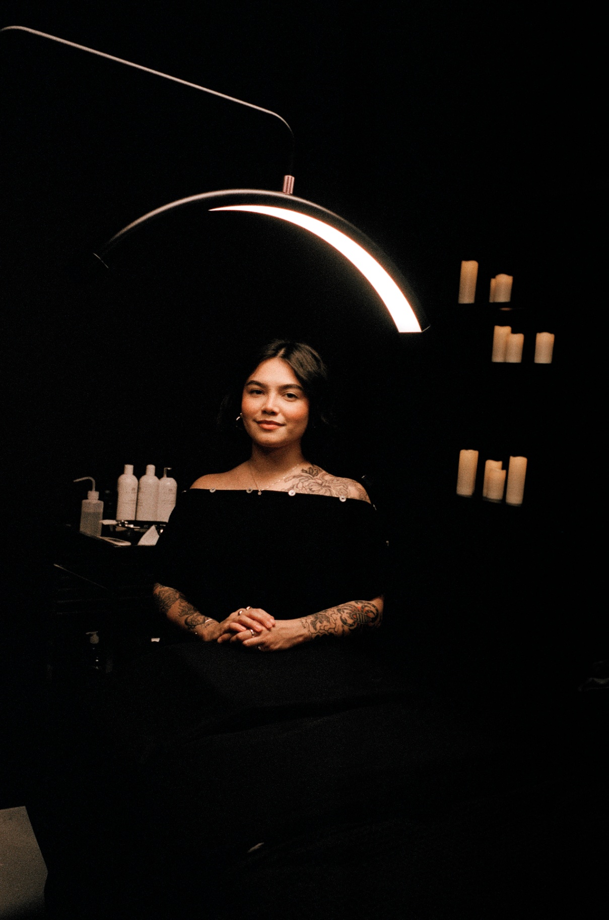 Sacred Skin's esthetician seated under a warm ring light in the treatment room